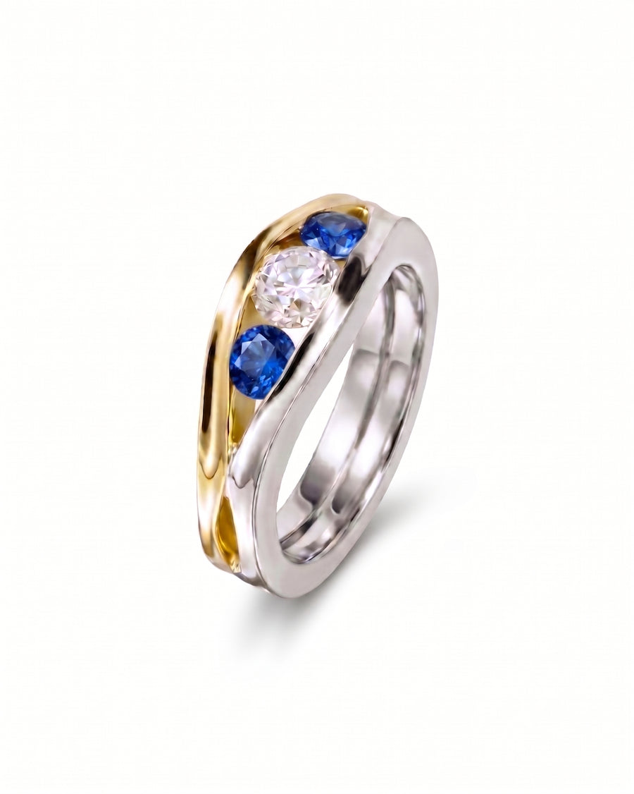 Gold and silver ring with three oval gemstones: two blue sapphires and one diamond.