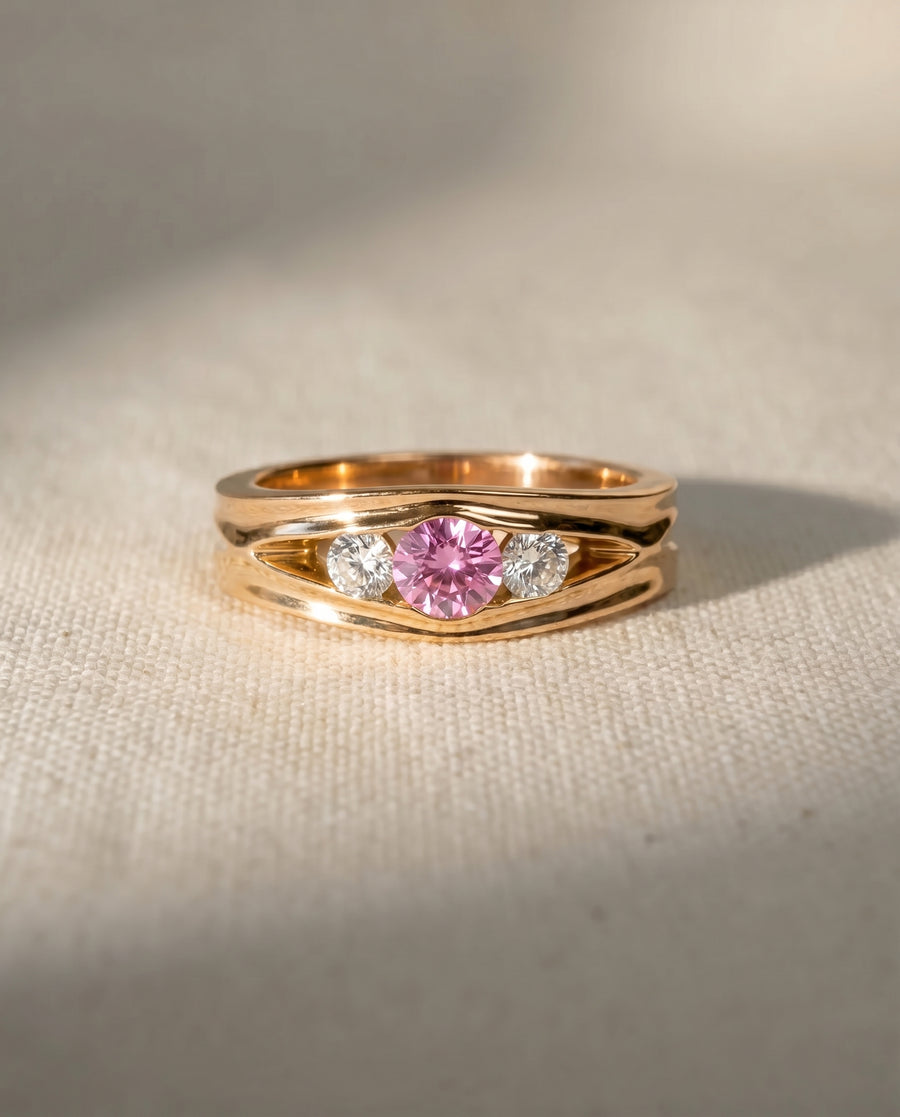 Rose gold ring with a pink sapphire and two round diamonds.