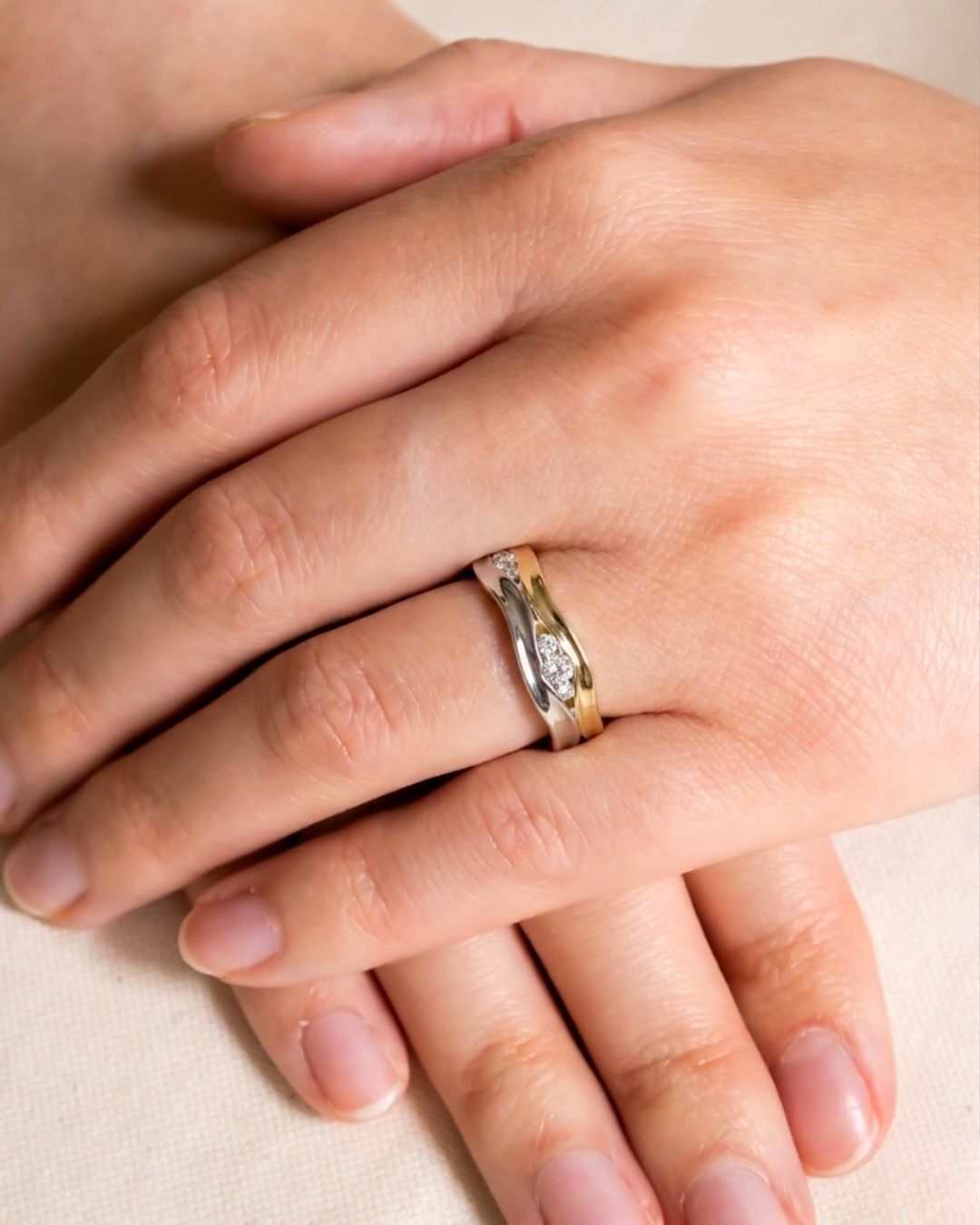 Two-colour gold diamond ring with a trap design on a hand.