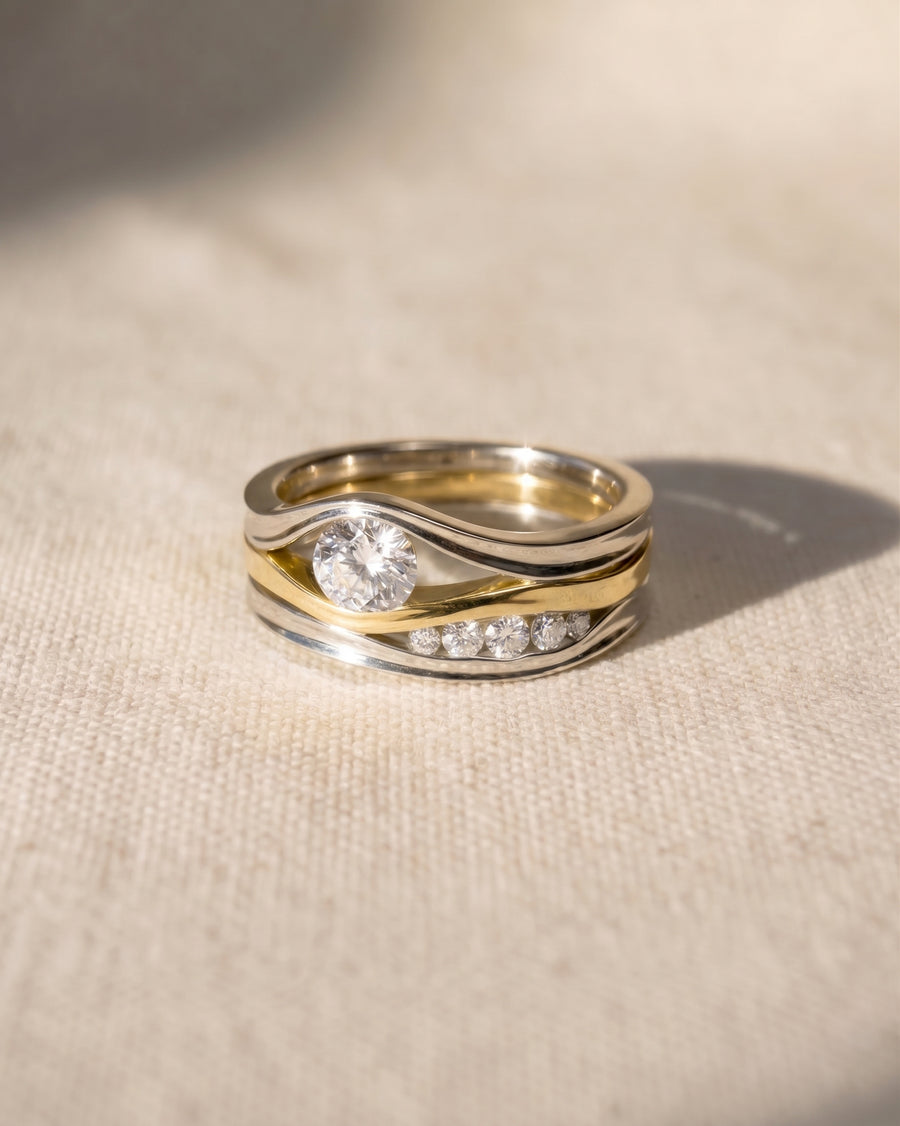 White and yellow gold three-band diamond ring with a large center stone and smaller accent diamonds.