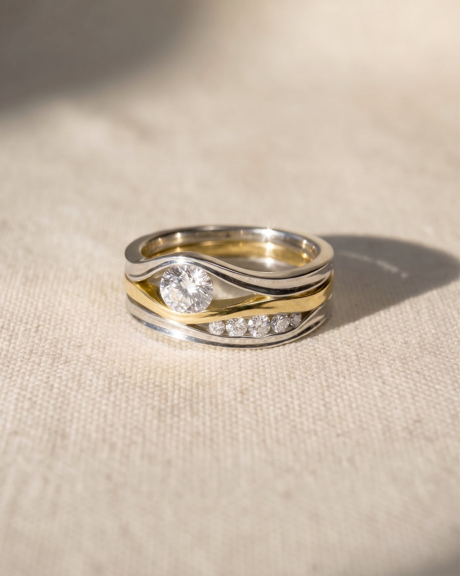 Platinum and yellow gold three-band diamond ring with a large center diamond and five smaller diamonds.