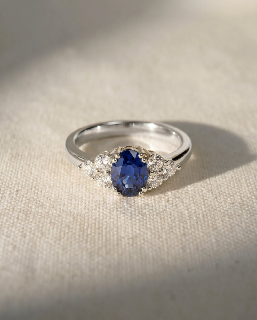 Platinum engagement ring with an oval sapphire and trefoil diamond accents.