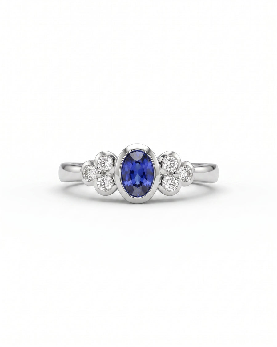 White gold engagement ring with an oval blue sapphire and trefoil diamond clusters.