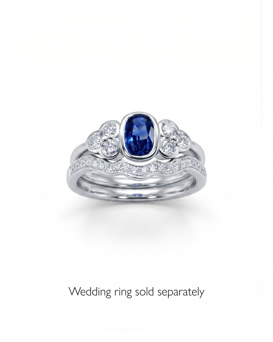 Platinum trefoil engagement ring with an oval blue sapphire and diamond clusters.