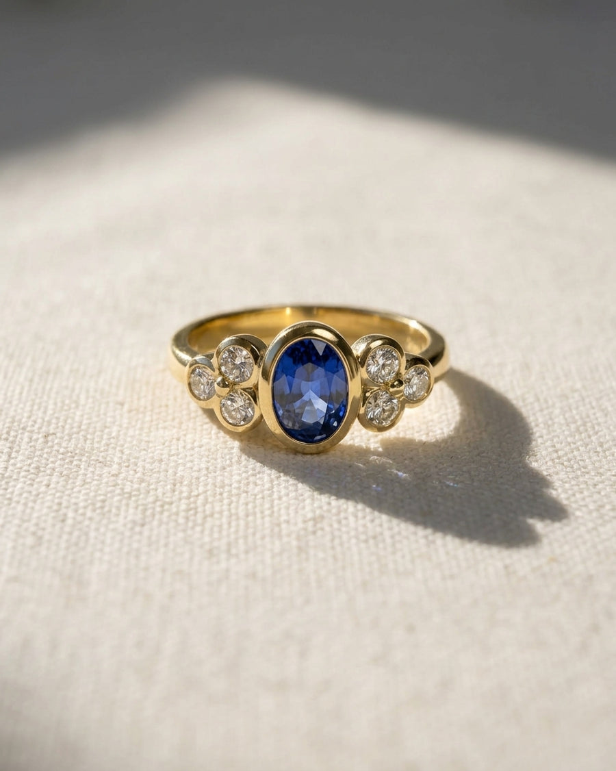 Gold engagement ring with an oval blue sapphire and six round diamonds.