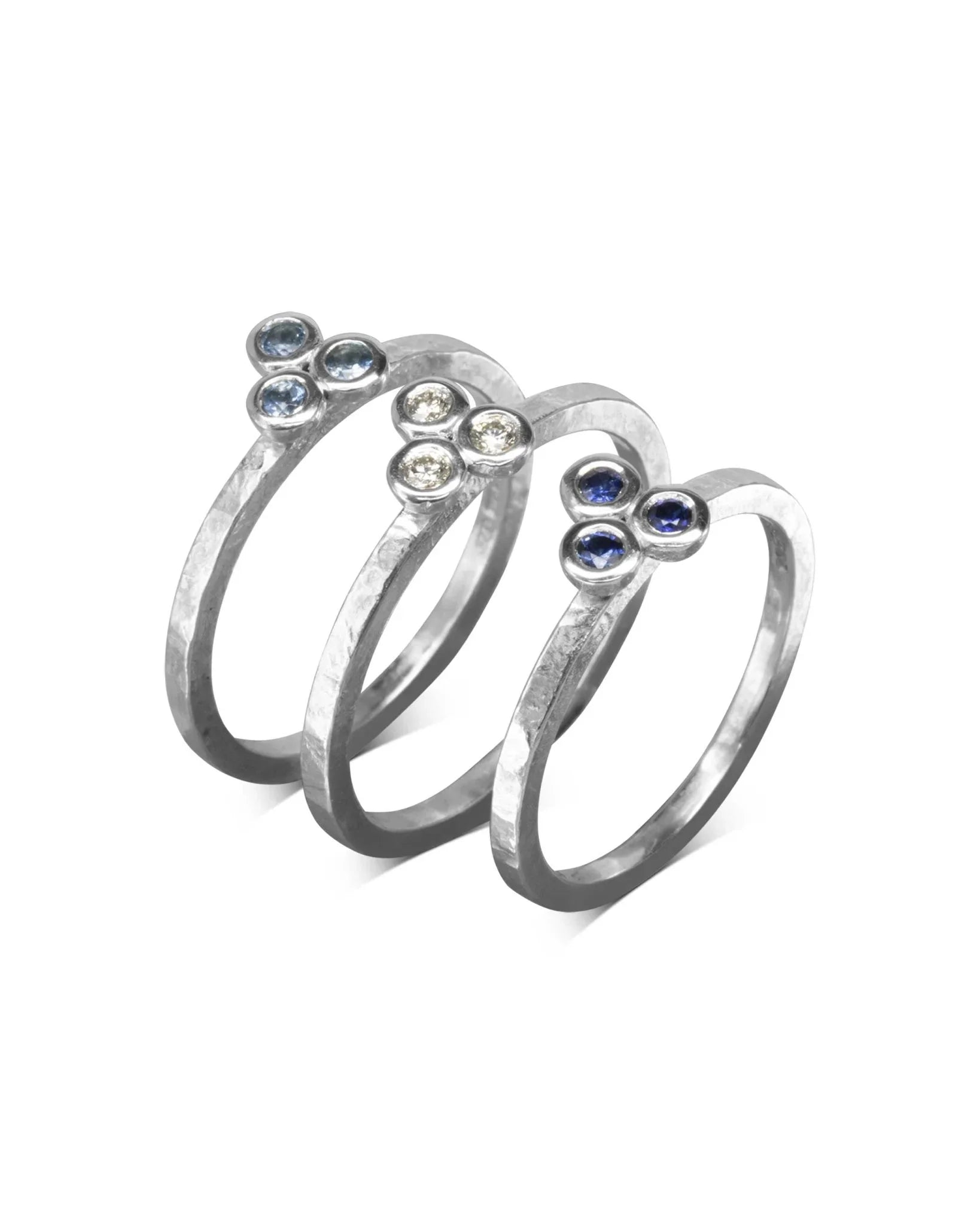 Three hammered gold stackable rings with trefoil gemstone diamonds.