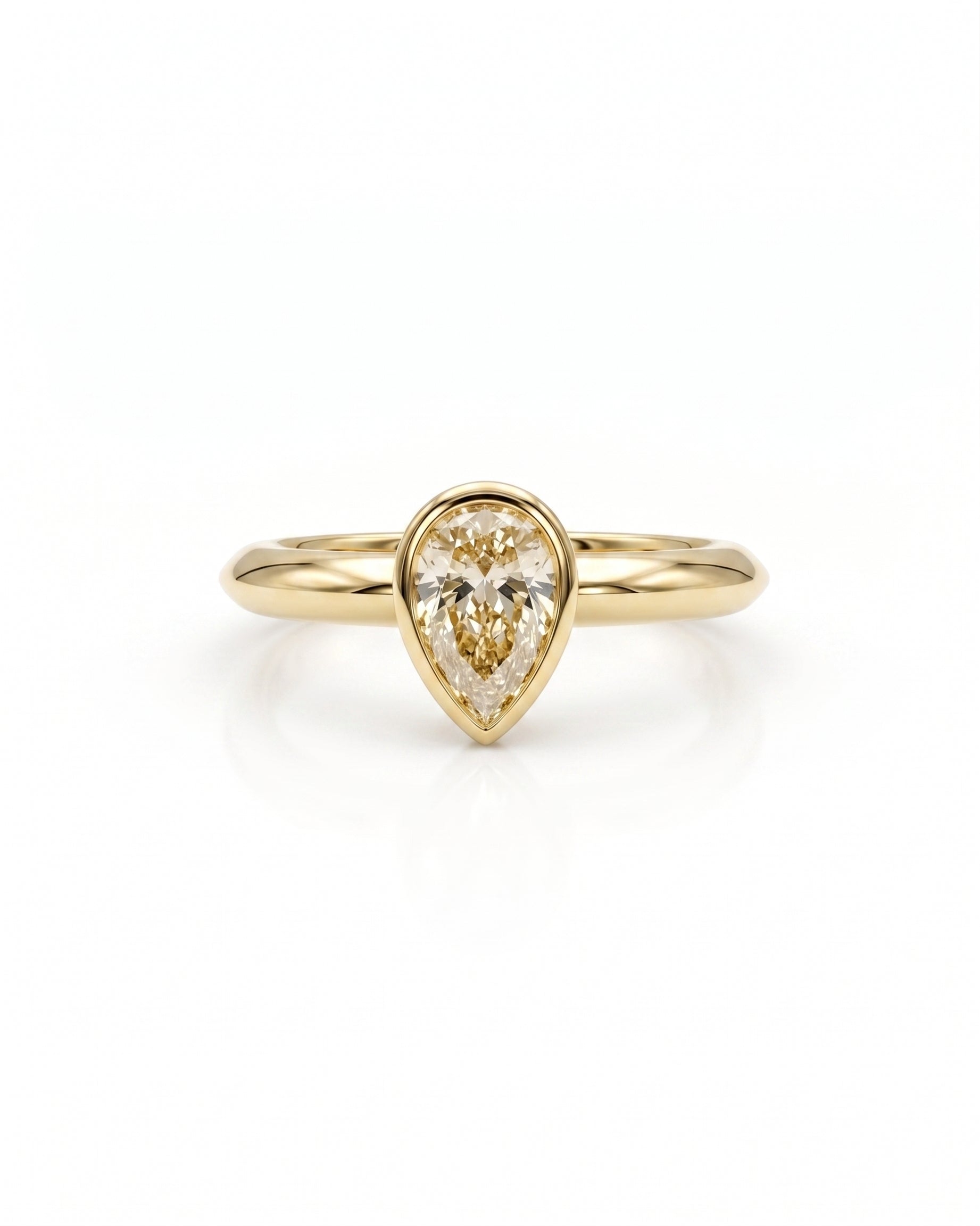 Yellow gold ring with a pear cut diamond in a bezel setting.