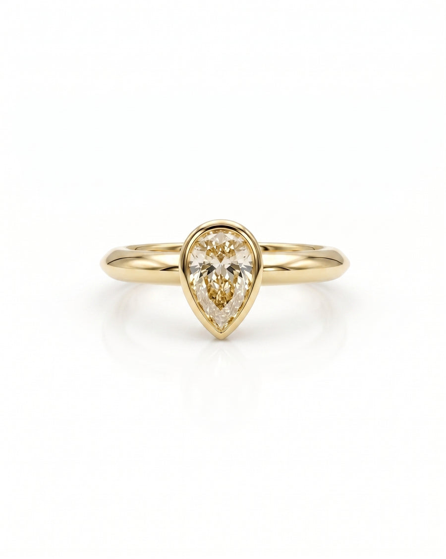 Yellow gold ring with a pear cut diamond in a bezel setting.
