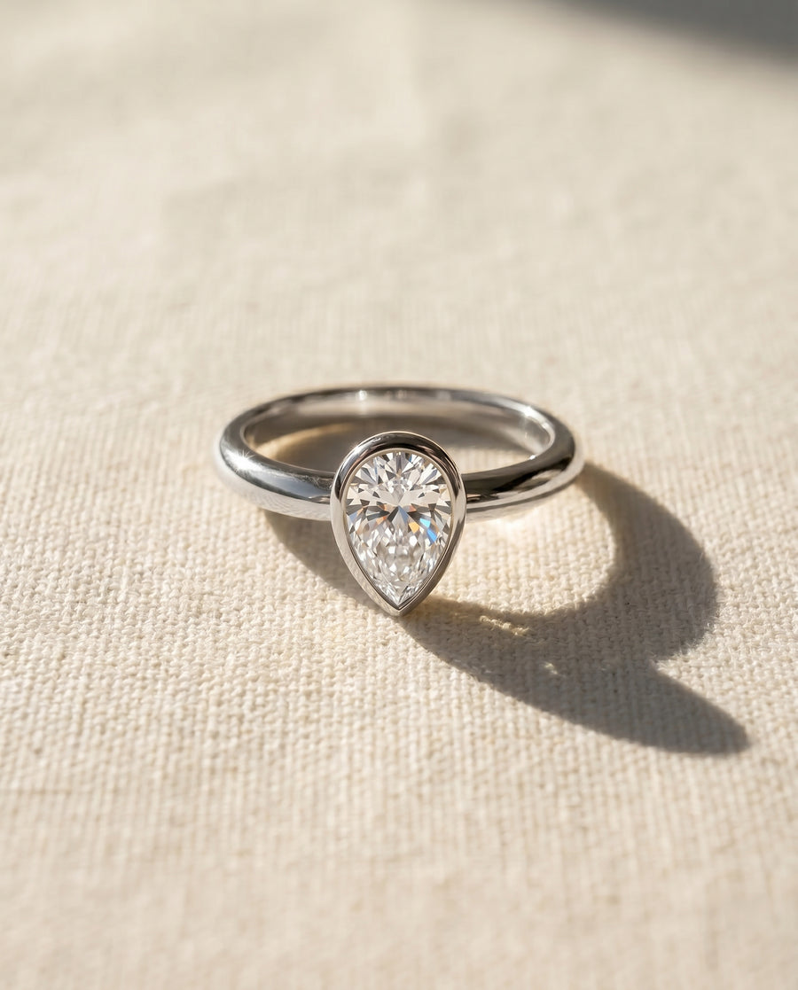 9ct white gold ring with a pear cut diamond in a bezel setting.