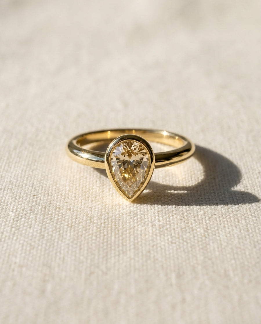 9ct yellow gold ring with a pear cut diamond in a bezel setting.