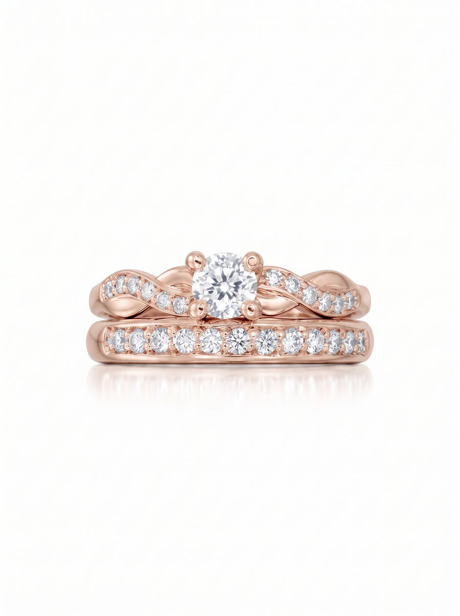 Rose gold engagement ring and wedding band set with a round diamond and pavé-set stones in a twisted design.