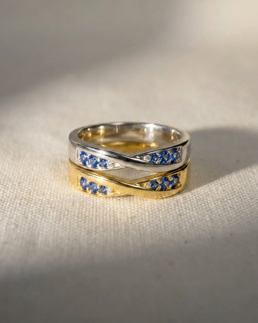 Two twist sapphire rings, one silver and one gold, with small diamonds.