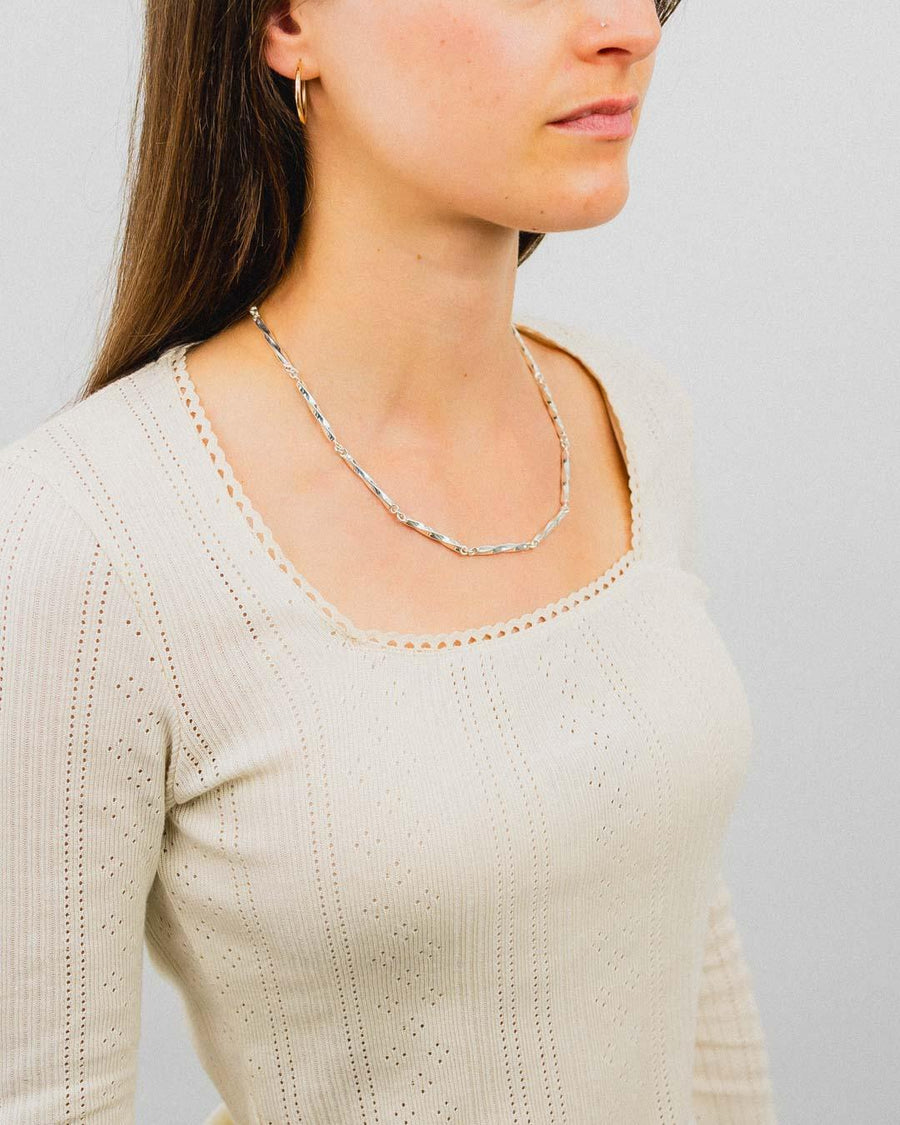 Woman wearing a handmade twisted silver chain necklace with a patterned cream top
