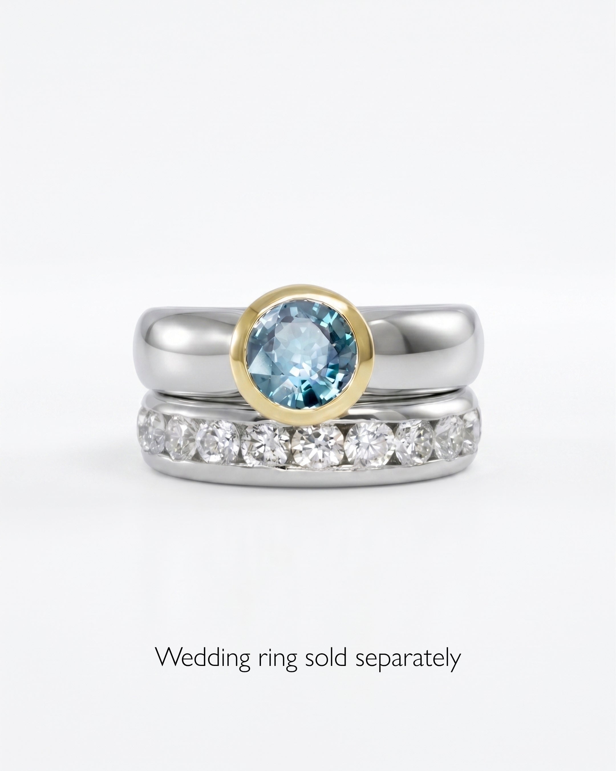Two-tone engagement ring with a round blue gemstone and a silver band.