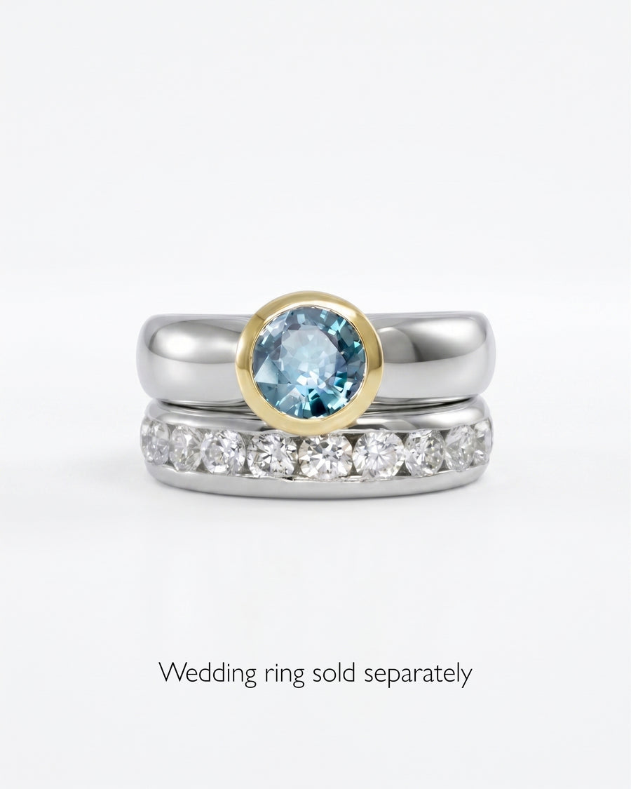 Two-tone engagement ring with a round blue gemstone and a silver band.