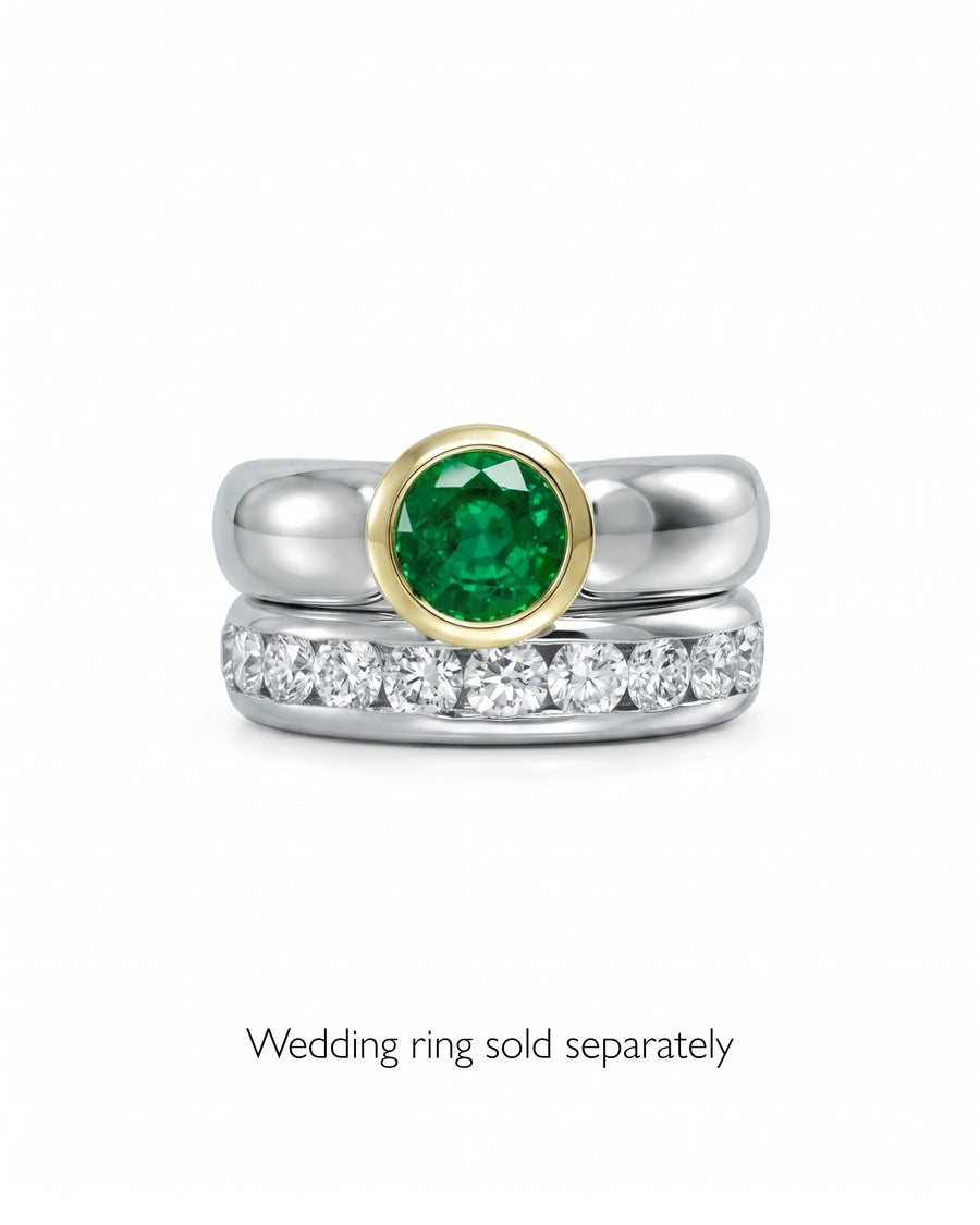 Two-tone gold and silver ring with a round emerald and a silver band with diamonds.