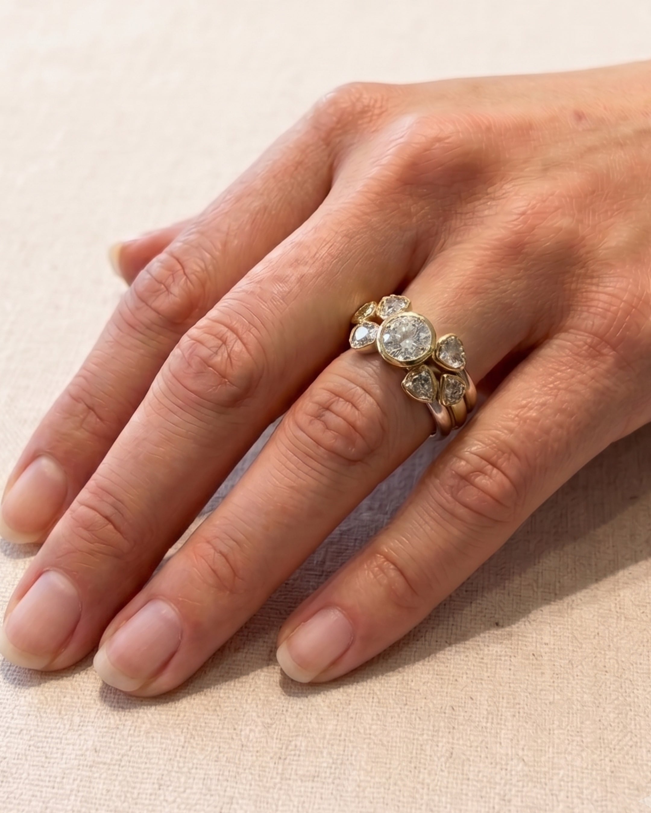 Two-tone gold stacking rings featuring a central round brilliant diamond surrounded by smaller rough-cut diamonds.