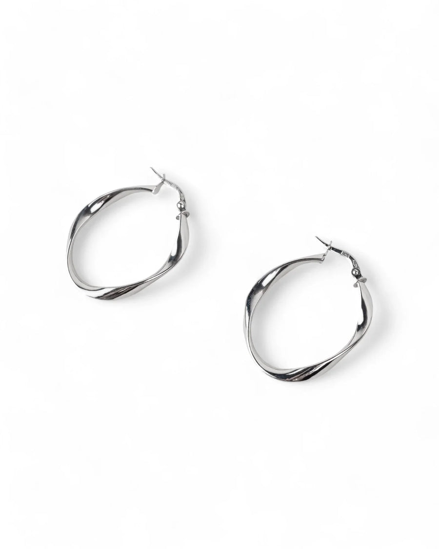 Uneven twisted yellow gold hoop earrings with organic, handcrafted texture on white background