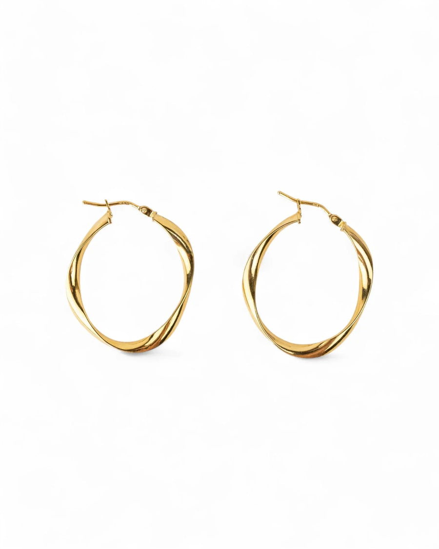 Twisted gold hoop earrings with organic, uneven design on white background