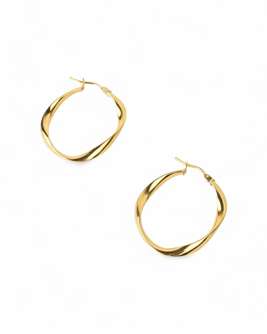 Uneven twisted gold hoop earrings with organic shape on white background