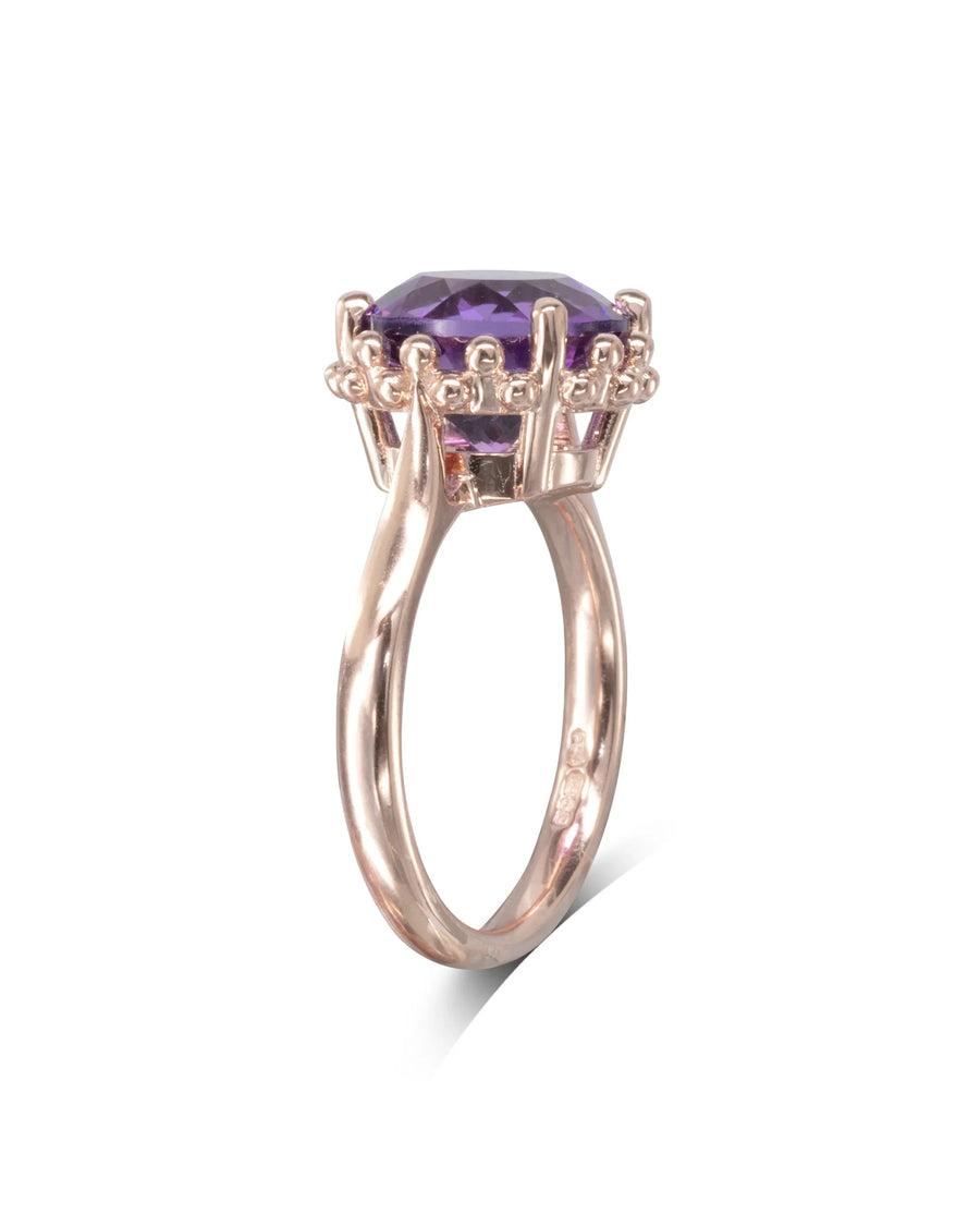 Gold ring with faceted round amethyst gemstone in ornate claw setting