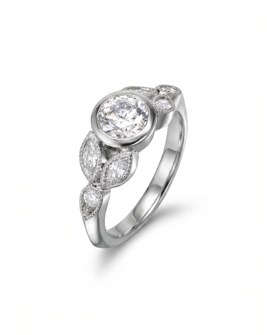 Silver bezel set diamond engagement ring with marquise and round side stones.
