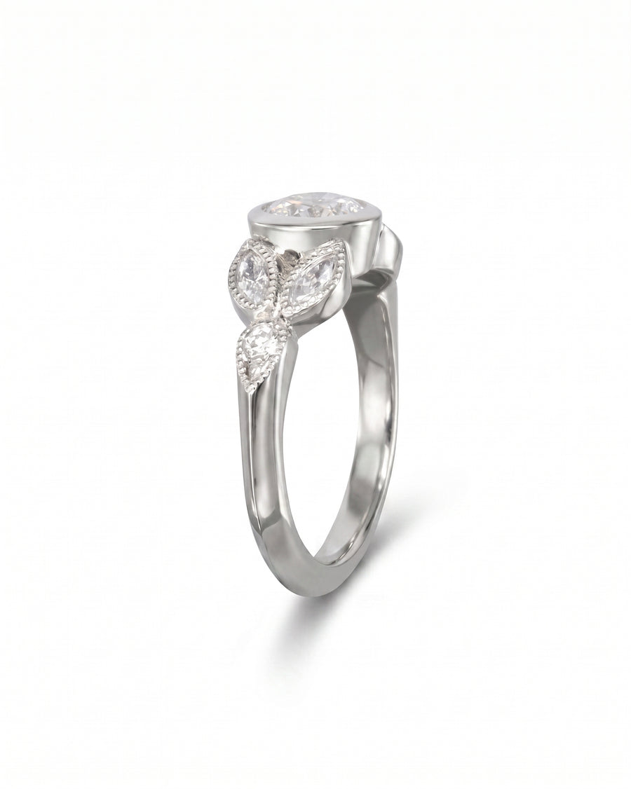 Silver engagement ring with a bezel-set diamond and three marquise accent diamonds.