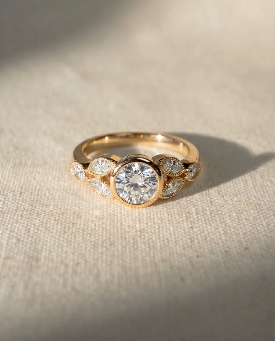 Gold bezel set diamond engagement ring with marquise side stones.