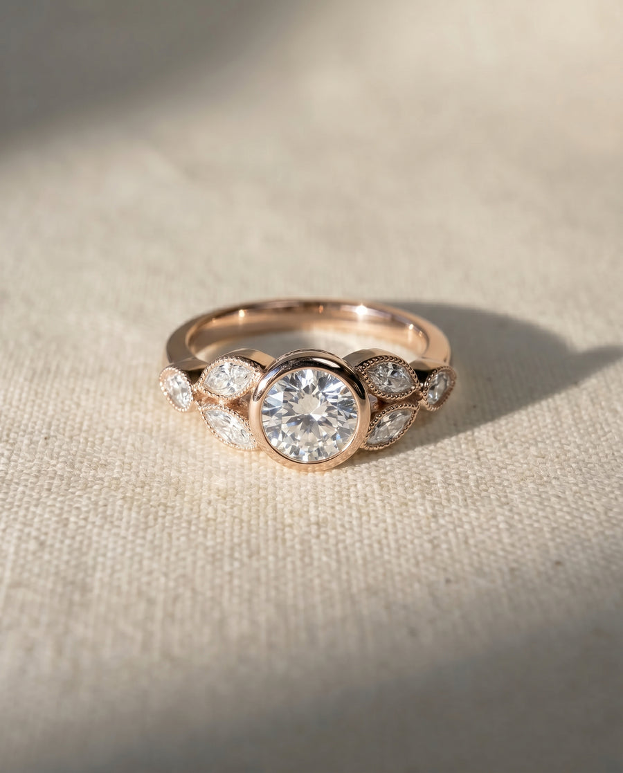 Rose gold bezel set diamond engagement ring with marquise accents.