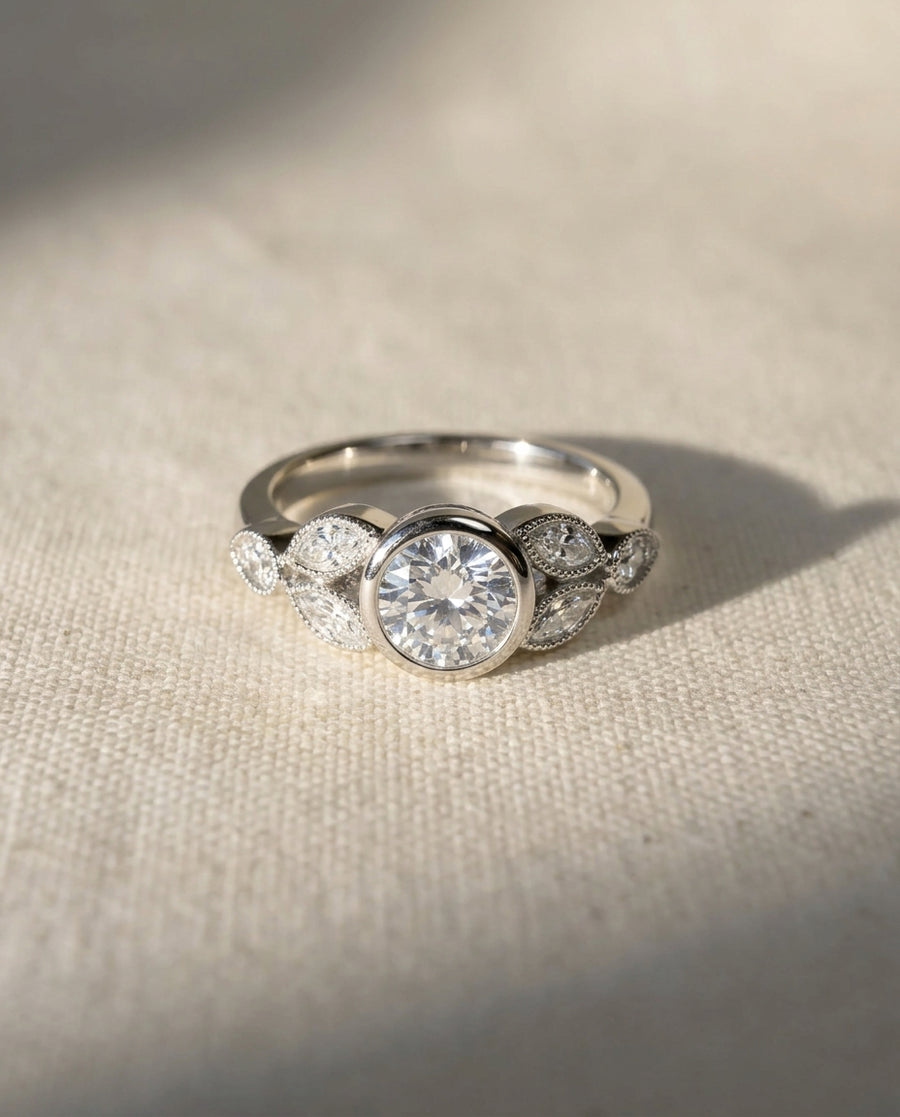 Platinum bezel set diamond engagement ring with marquise accents.
