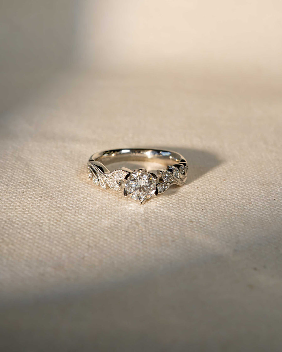 Silver ring with a round diamond center stone and beaded leaf design.