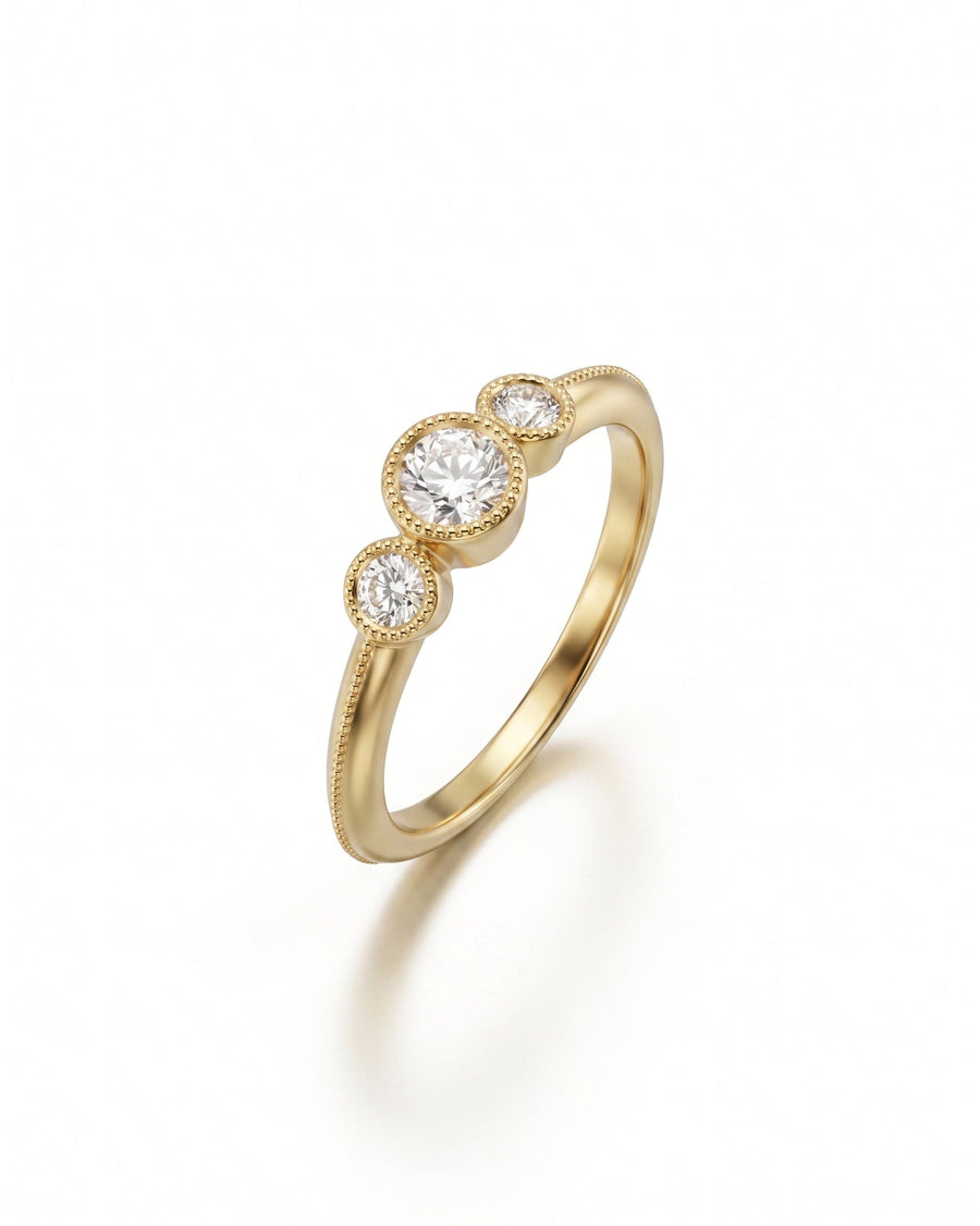 Gold trilogy engagement ring with three round diamonds and milgrain detailing.
