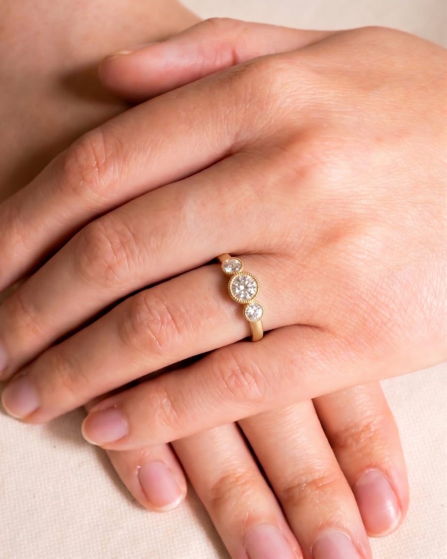 Gold vintage diamond trilogy engagement ring on a hand.
