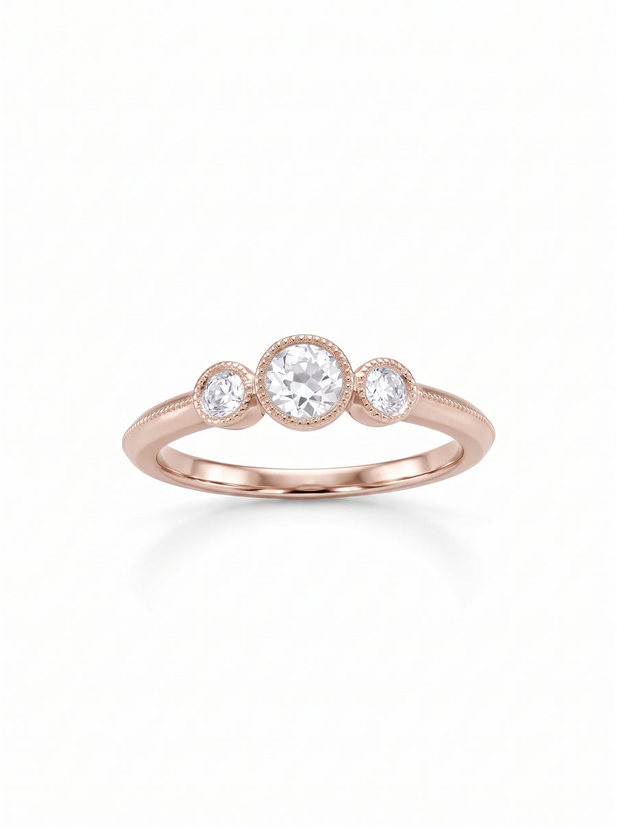 Rose gold trilogy engagement ring featuring three round diamonds in milgrain bezel settings on a polished band.