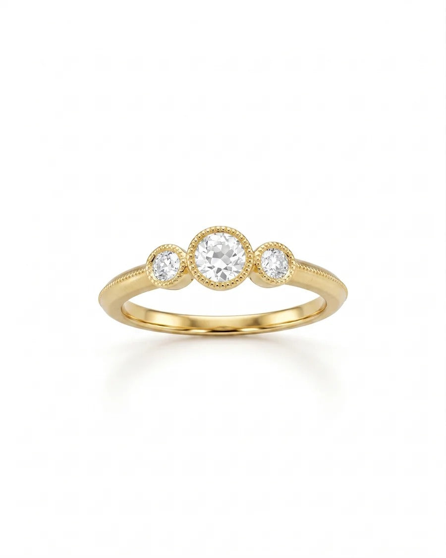 Yellow gold trilogy engagement ring with three round diamonds in milgrain bezel settings.