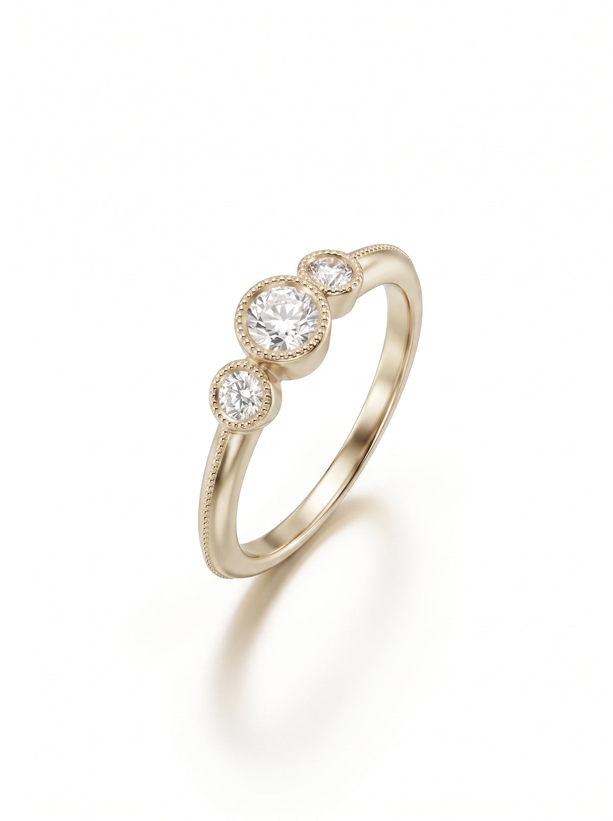 Yellow gold trilogy engagement ring featuring three bezel-set round diamonds with milgrain detailing on the band.