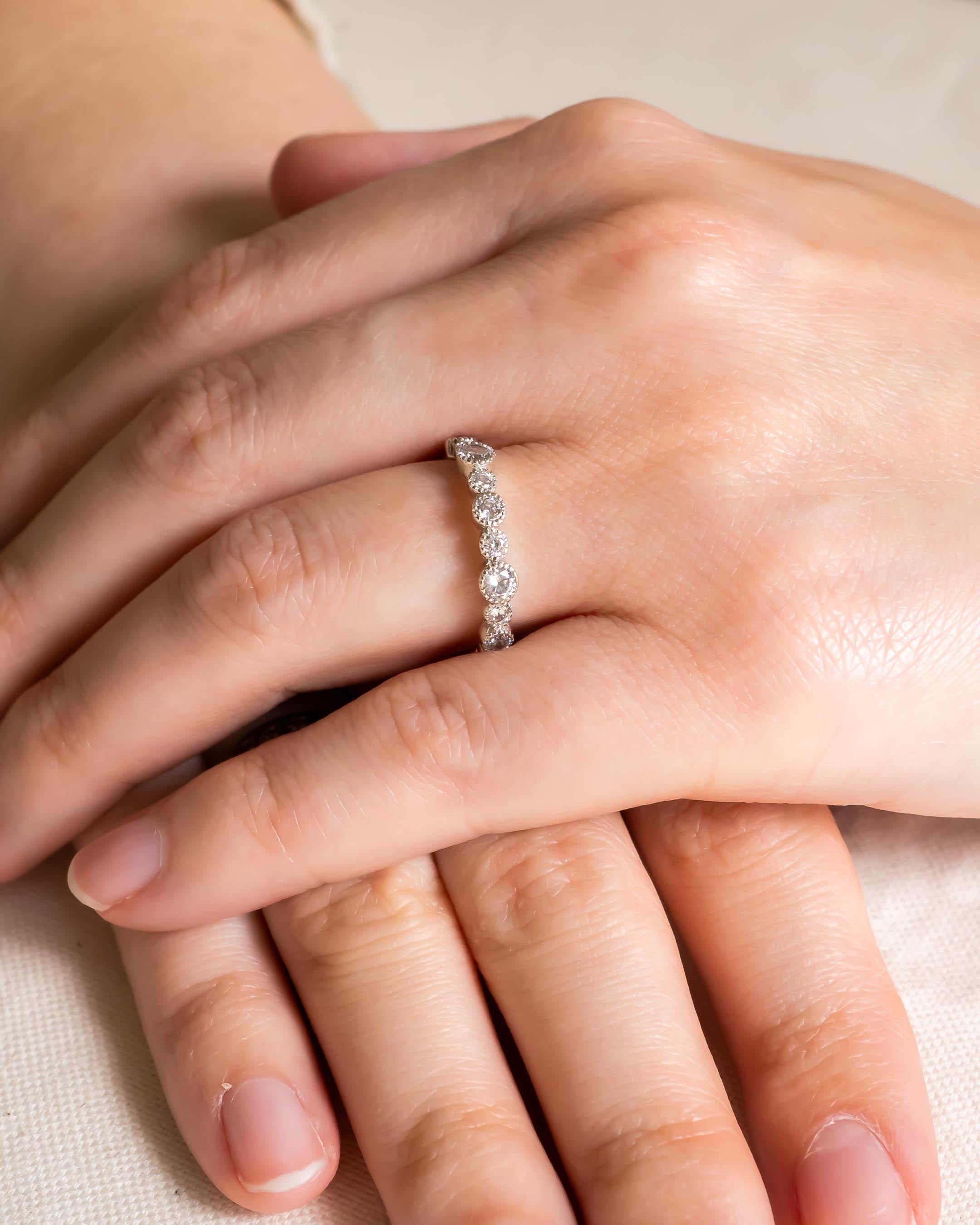 Silver eternity ring with round diamonds on a hand.