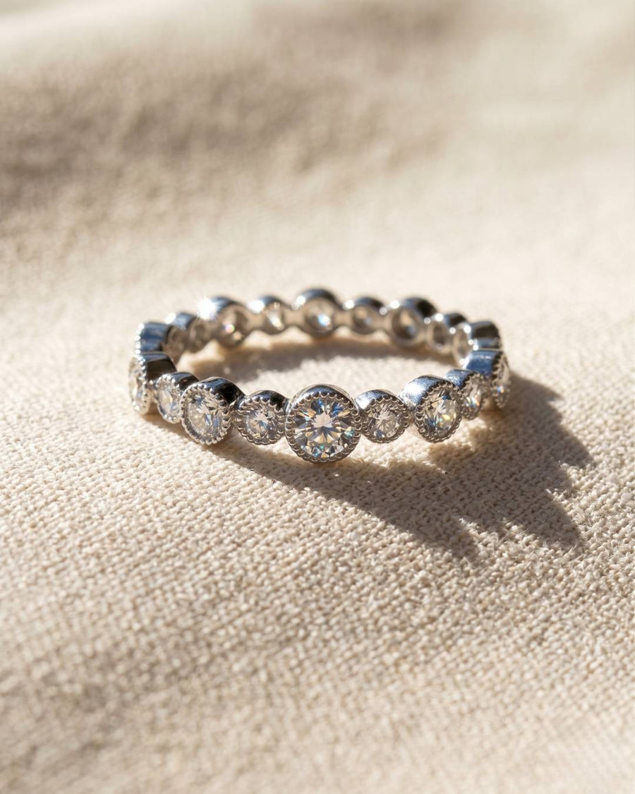 Silver eternity ring with round diamonds in bezel settings.