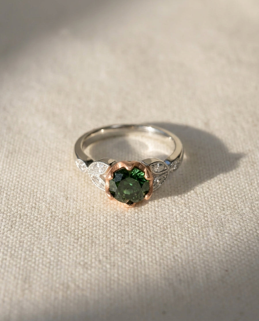 White gold ring with a round green diamond and rose gold accents.