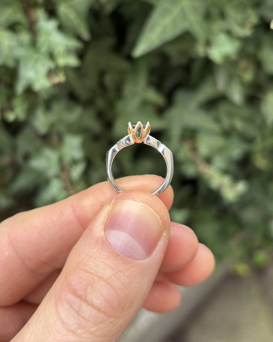 Silver and rose gold ring with a green diamond and side diamonds.
