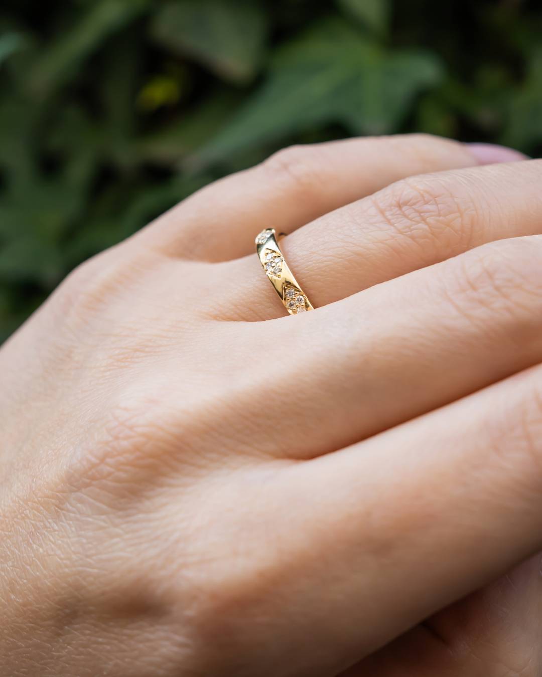 Gold ring with vintage-look diamond pattern worn on a hand.