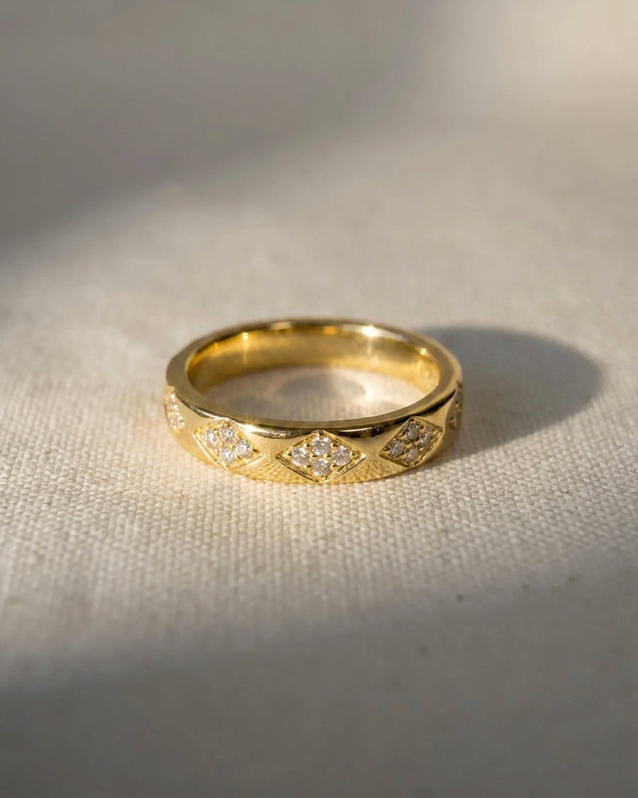Gold ring with a diamond pattern and small clear gemstones.
