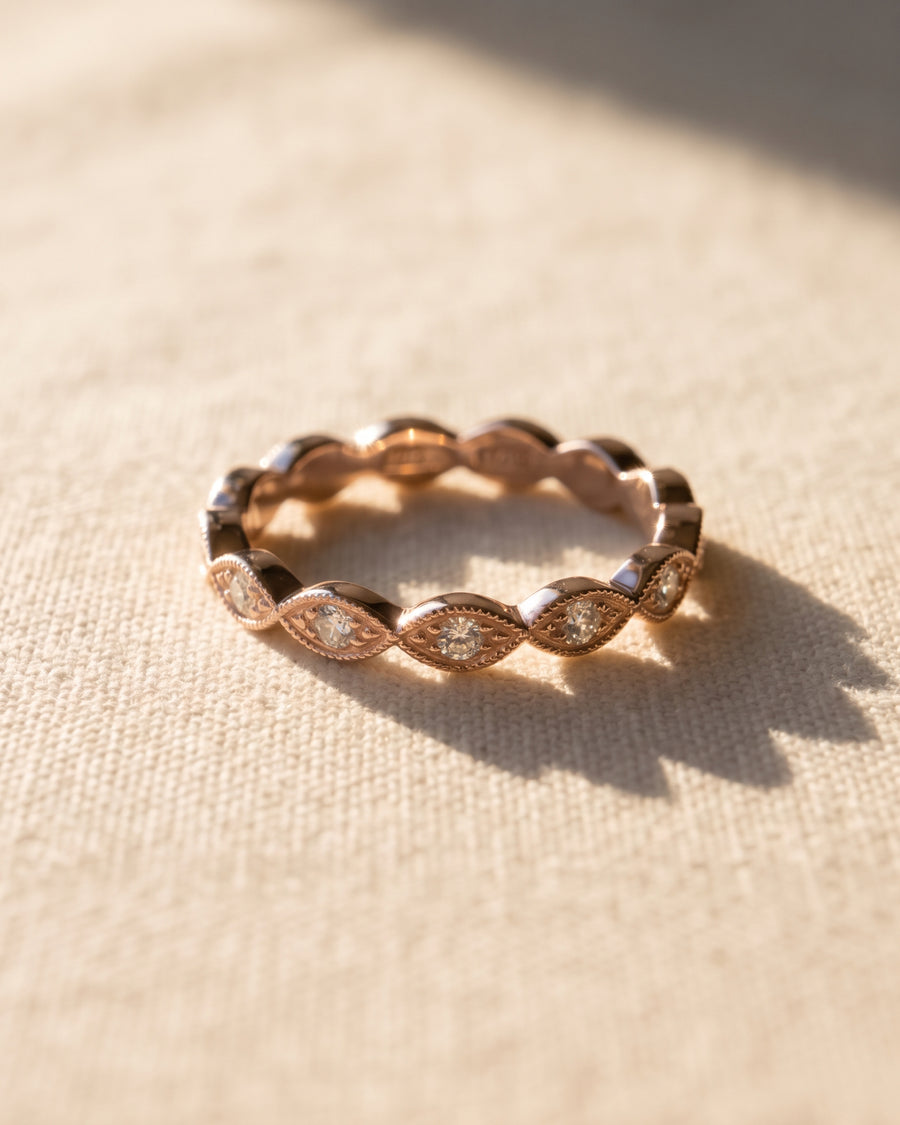 Rose gold eternity band featuring marquise-shaped settings with round diamonds on a textured fabric background.