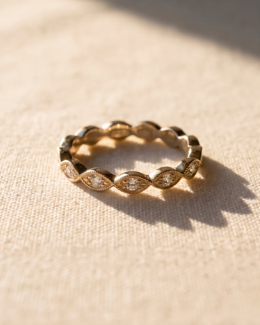 Gold band ring featuring marquise-shaped settings with small round diamonds and milgrain detailing.