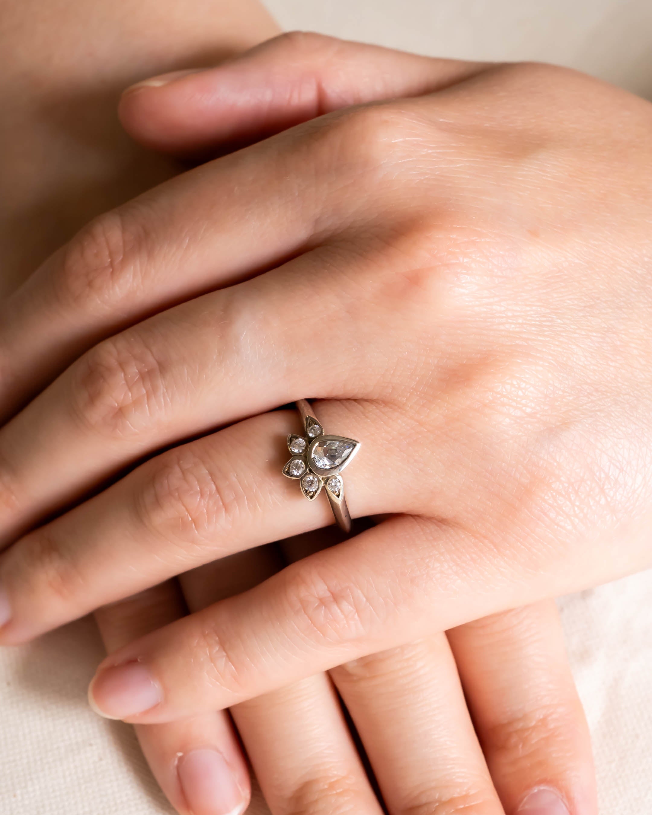 Vintage peacock diamond cluster engagement ring on a hand.