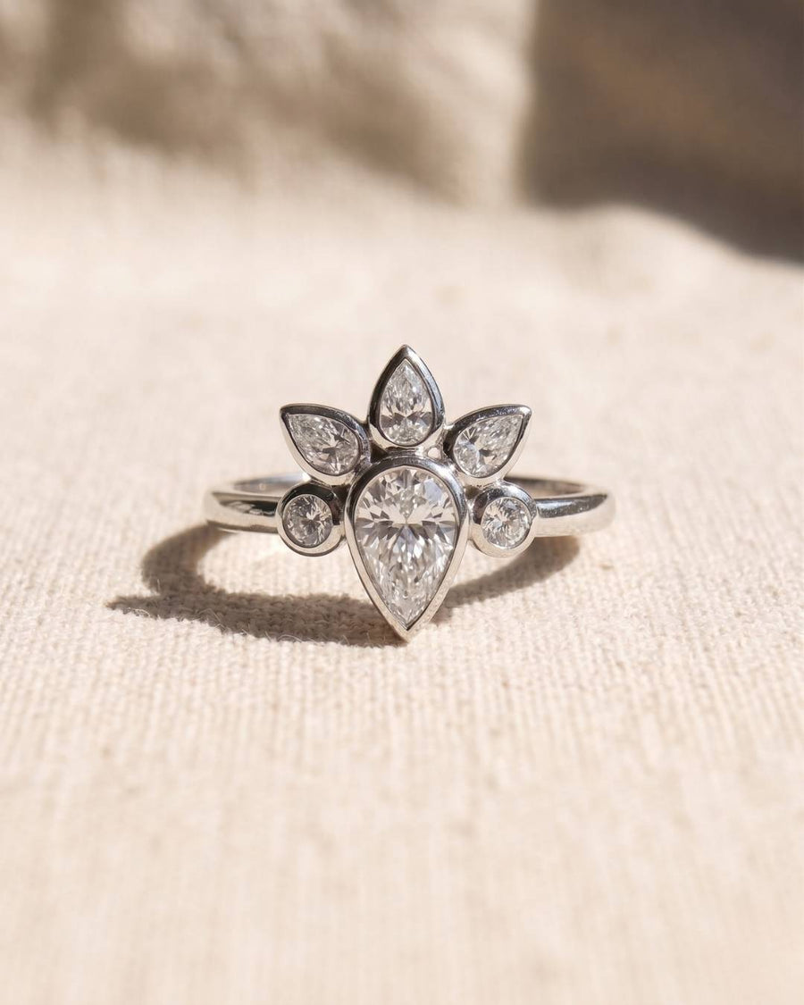 Platinum engagement ring with a pear-shaped diamond surrounded by marquise and round diamonds.
