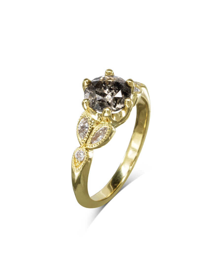 Gold engagement ring with a salt and pepper diamond and leaf-shaped side stones.