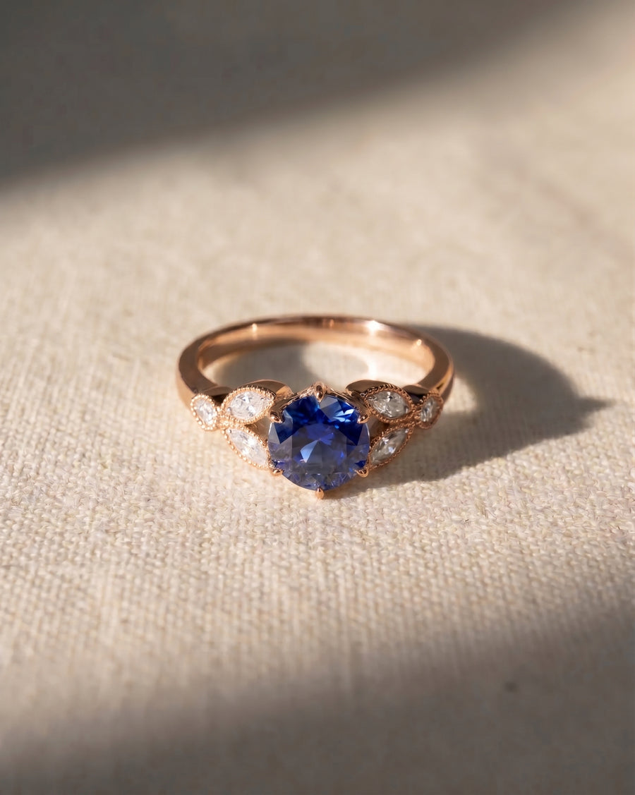 Rose gold ring with a round sapphire and marquise diamonds.