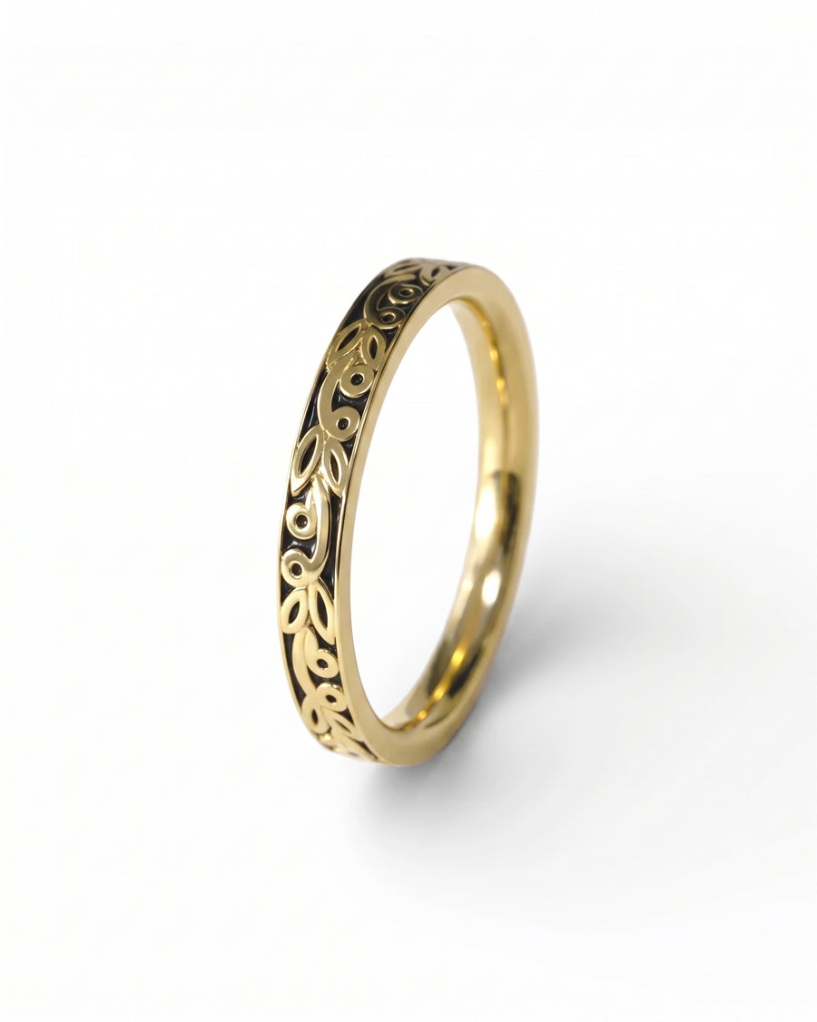 Gold wedding ring with carved black floral design.