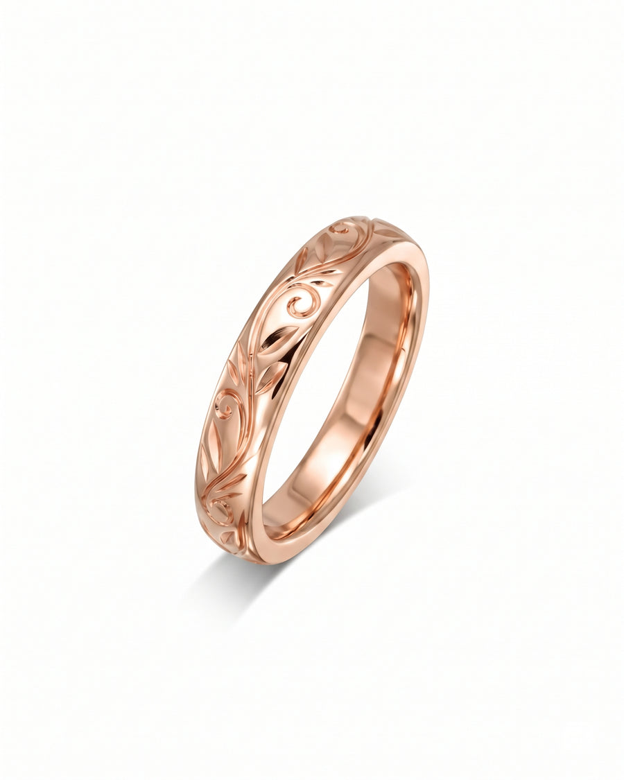 Rose gold wedding ring with an intricate engraved floral leaf pattern on a polished band.